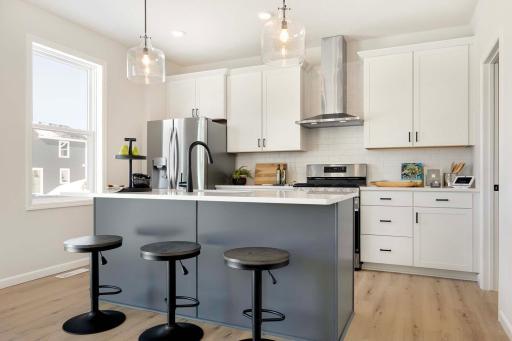 Kitchen includes quartz countertops, ceramic tile backsplash, gas stove and stainless steel hood vented to exterior.