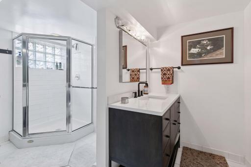 Lower level 3/4 bath features a vanity sink, tile floor and block windows.