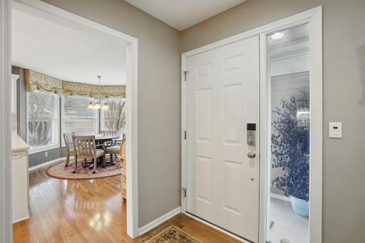 Step inside to a bright entryway featuring solid oak hardwood floors that flow into the informal dining area, surrounded by windows and filled with natural light.