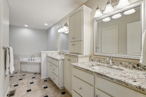 The remodeled ownerâs bath features granite countertops, dual sinks, updated faucets, and a center storage towerâblending style and function for everyday comfort.