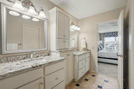 A second angle of the dual-sink vanity shows the spacious layout of the ownerâs bath, with a clear view back into the bedroomâcreating a seamless flow between spaces.