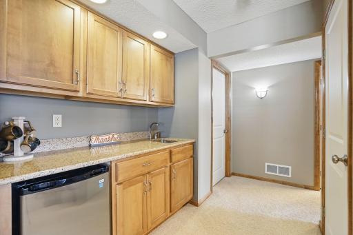 The lower-level wet bar features solid surface countertops and ample cabinet storageâperfect for entertaining or keeping refreshments easily accessible.