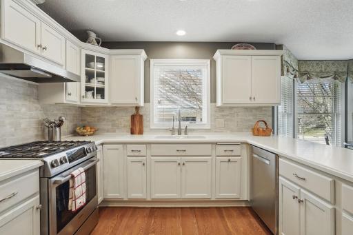 A large window above the sink lets in natural light, while white cabinets and modern hardware add a clean, updated look.
