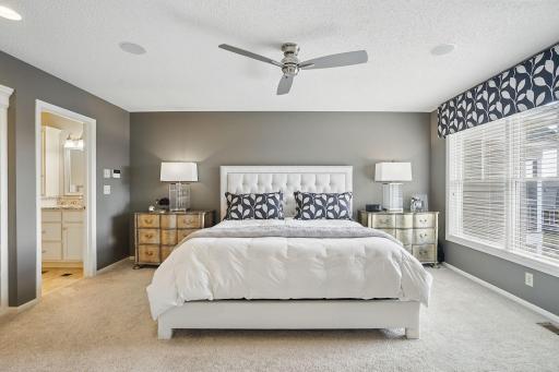 French doors open to the spacious ownerâs suite, offering a private retreat with large windows, custom window treatments, and a cozy sitting area surrounded by built-in bookshelves.