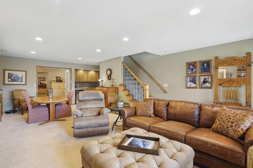 The spacious family room extends into a flexible area perfect for a game table or hobby space, complete with recessed lighting, a convenient wet bar, and custom railings along the staircase that add a touch of craftsmanship and style.
