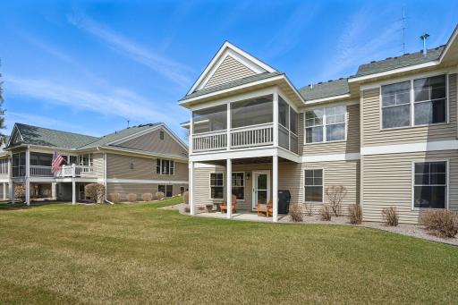 Another view of the back of the home showcases the screened porch, walkout patio, and well-kept yardâhighlighting the homeâs thoughtful design and connection to the outdoor space.