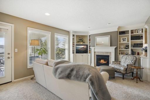 The living room features a cozy gas fireplace, custom built-ins, and a door leading to the vaulted screened porchâoffering an easy transition to outdoor relaxation.