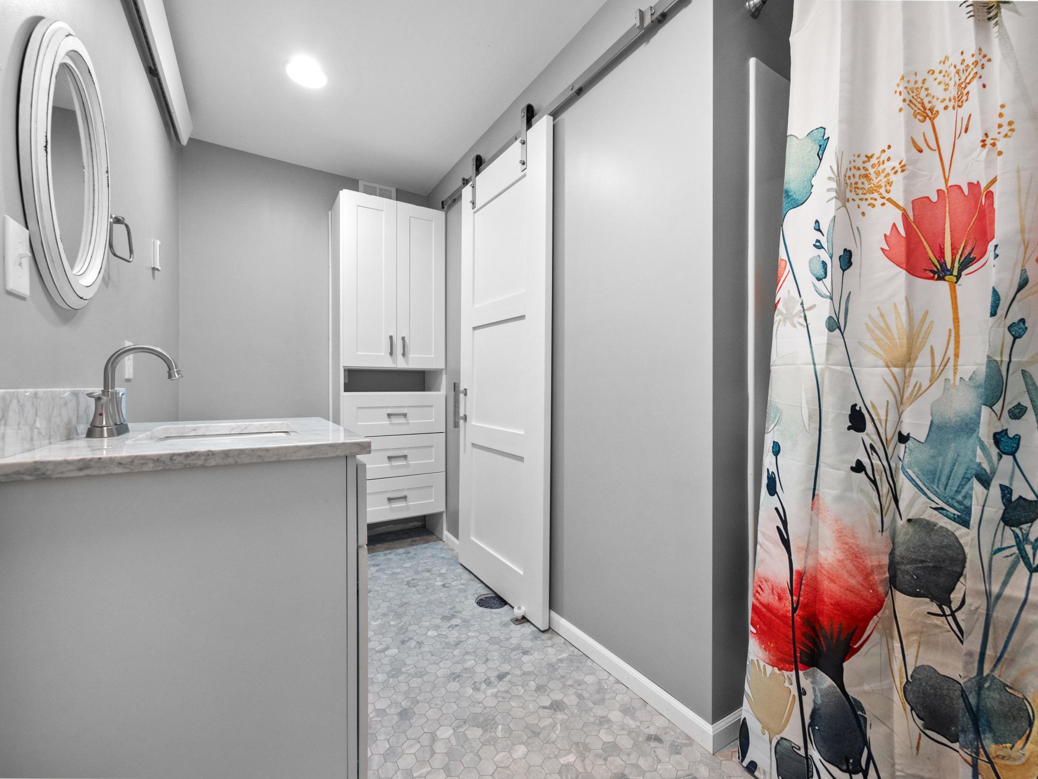 Check out the beautiful finishes! The walk in shower is behind the curtain. The toilet is on the other side of the vanity. And the stylish barn door leads to the utility room.