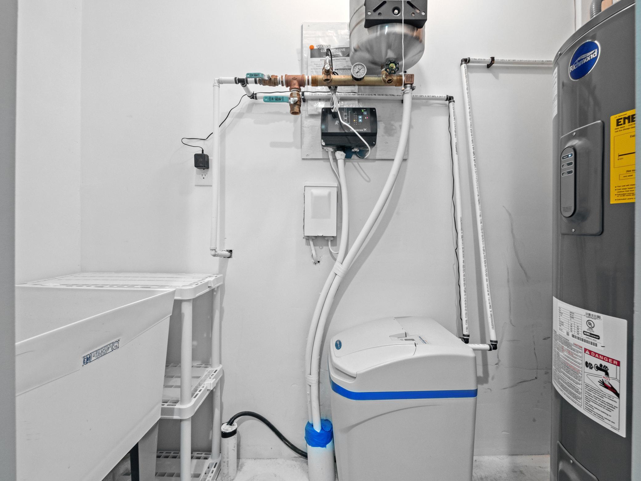 The utility room includes a hot water heater, water softener and laundry tub.