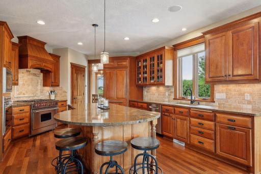 The Kitchen features custom cherry cabinetry with glass-front cabinets, top-tier granite countertops, and a walk-in pantry.