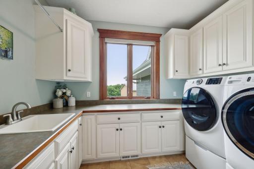 Bright and fresh, the Laundry Room is equipped with a new GE washer and dryer set with pedestals, extensive cabinetry and a large folding counter.