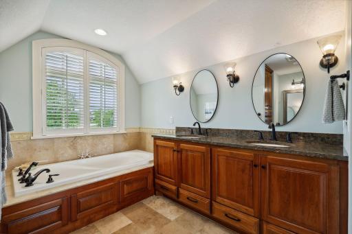 The spa-worthy Primary Bathroom features heated tile flooring, a jetted bathtub and comfort-height vanity with granite countertops.