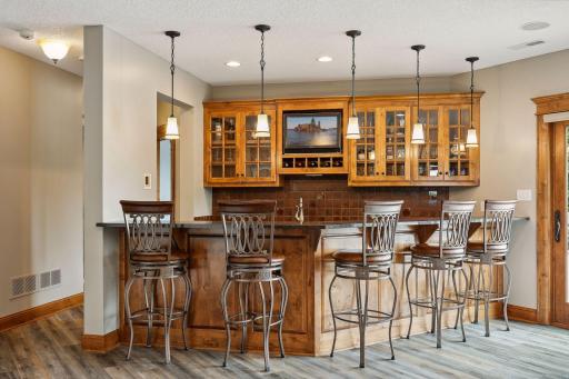 The wet bar features granite countertops, glass-front cabinetry and a beverage refrigerator.