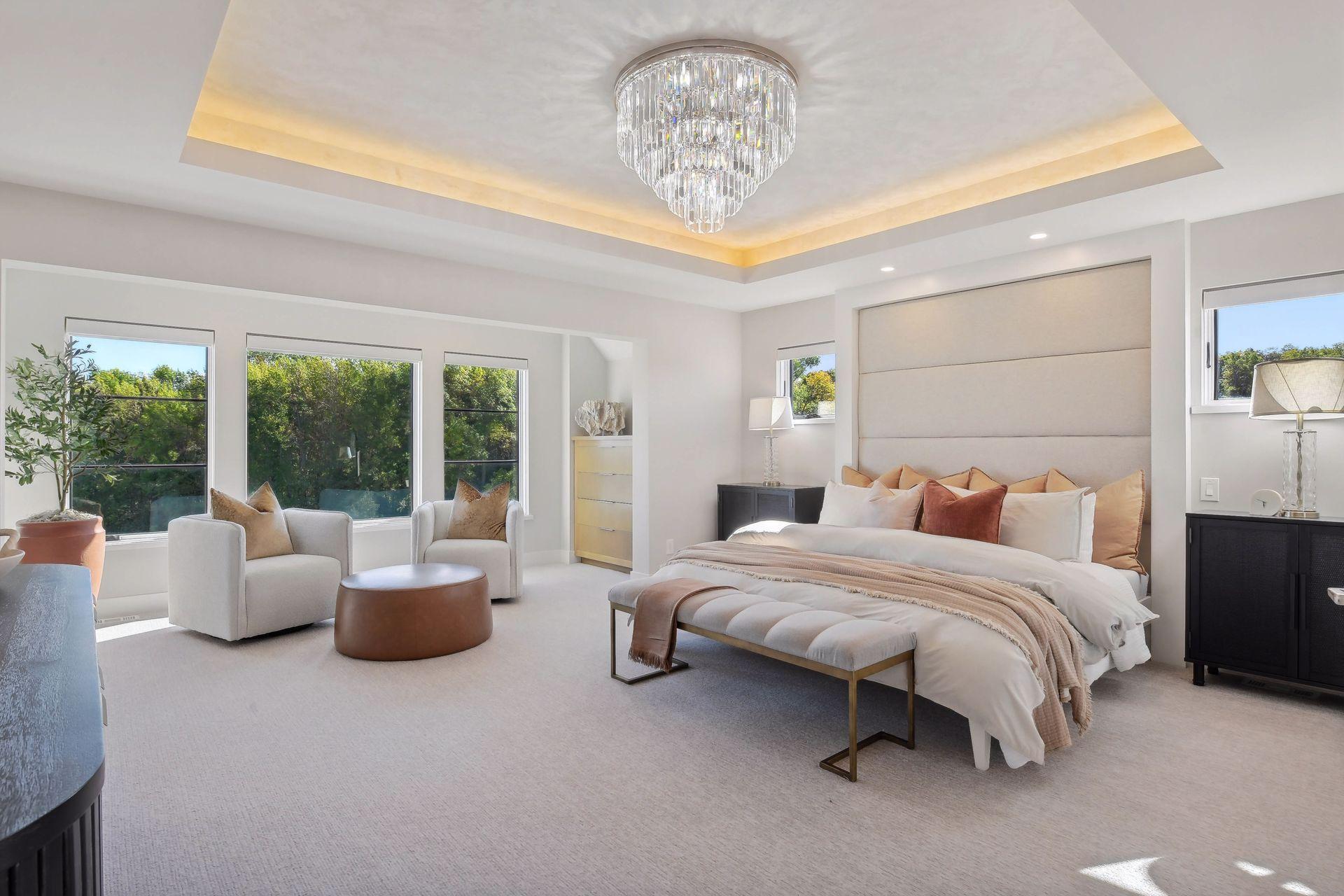 This grand primary bedroom is spacious and cozy with a dazzling chandelier