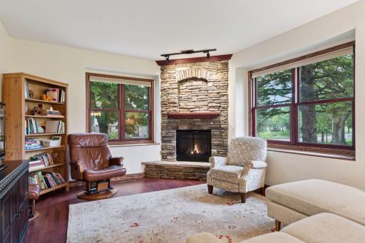 Welcoming front living room with gorgeous windows, 9ft ceilings, and a corner floor to ceiling stacked stone gas fireplace.