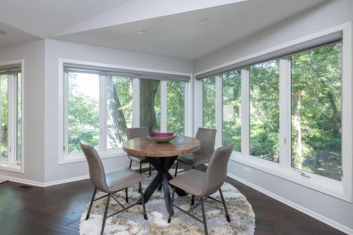 Informal dining area with windows on two sides overlooking backyard