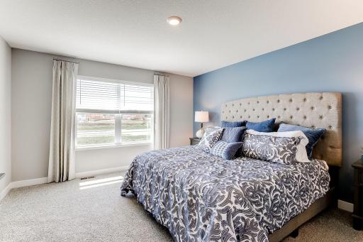 Primary Suite, shown here with a King-sized bed, the room is overly spacious and offers the perfect setting to start and finish each day in! Photo of model home similar to new Henry plan, color & options will vary.