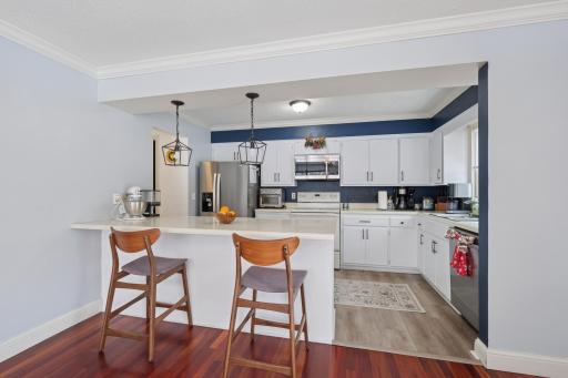 Open dining area flowing into the kitchen, ideal for entertaining. The end-unit design allows natural light to fill both spaces, enhancing the warm hardwood floors.