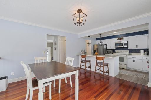 Open dining area flowing into the kitchen, ideal for entertaining. The end-unit design allows natural light to fill both spaces, enhancing the warm hardwood floors.