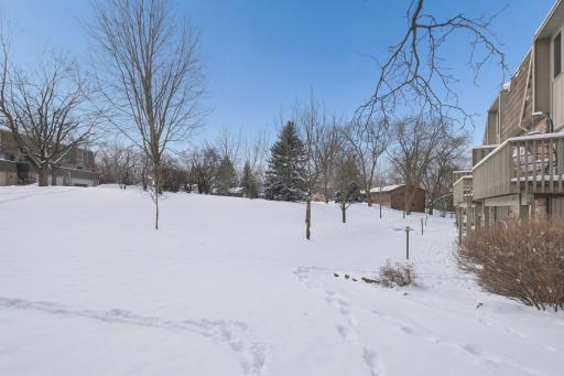 Exterior view highlighting the desirable end-unit location with added privacy and open green space. Mature trees surround the property for a peaceful setting.