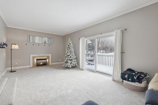 Sun-filled living room with neutral tones, fireplace, and seamless access to the deck. The open layout and end-unit exposure create a welcoming, spacious feel.