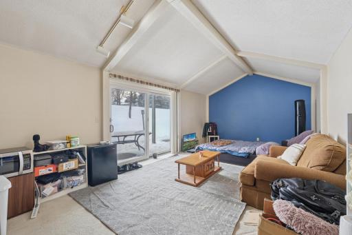 Spacious lower-level living area with vaulted ceilings and sliding glass doors to the outdoors. End-unit windows and glass doors fill the space with natural light, creating an open and inviting atmosphere.
