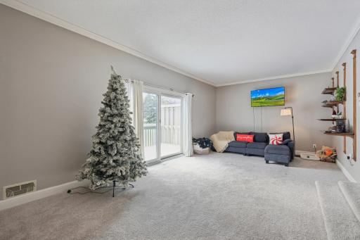 Bright and open main living area with plush carpet and large sliding glass doors leading to the deck. End-unit positioning offers generous natural light and peaceful outdoor views.
