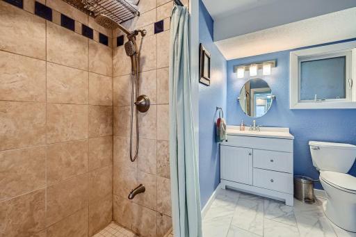 This main floor bathroom has a tile elegant tiled shower, vanity and toilet. Perfect for guests