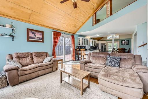 This home showcases a warm and inviting living room with an open-concept layout that flows seamlessly into the kitchen and dining areas. Entertaining made EZ with sliding glass doors that lead out to one of 3 deck areas