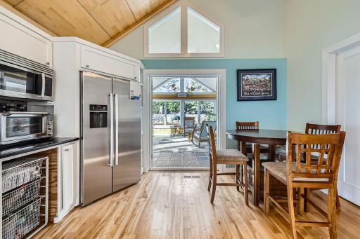 This bright and charming breakfast nook and kitchen area is perfect for casual dining or morning coffee. Custom cabinetry with slide-out wire pantry drawers add functional storage. Transom windows add daylight year round