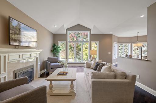 Relax in the spacious family room with its 9-foot vaulted ceilings, cozy gas-burning fireplace, and large windows showcasing stunning views.