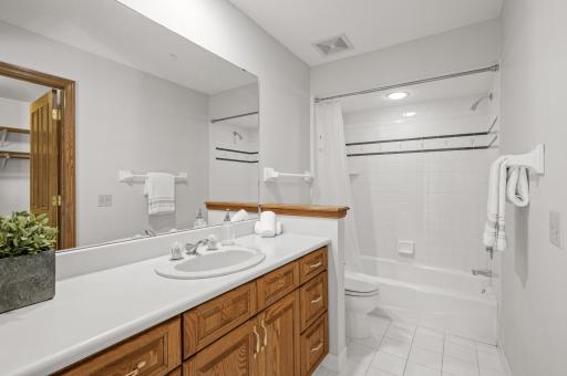View of the private bathroom with a tub/shower combo and tile surround.