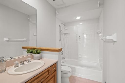 View of the private bathroom with a tub/shower combo and tile surround.