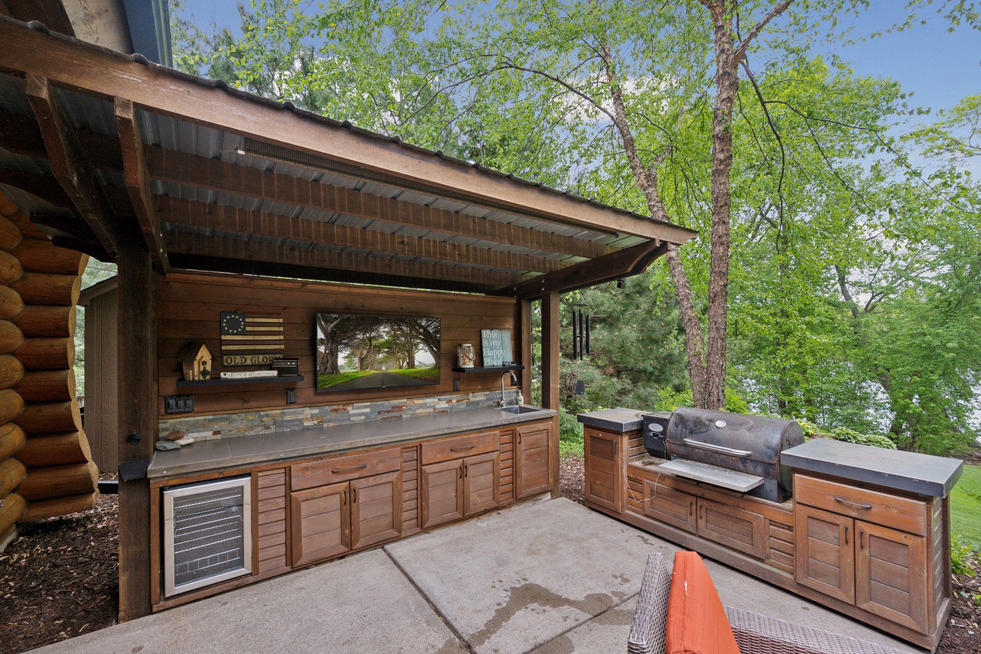 Awesome outdoor kitchen with TV area, beverage fridge, sink with hot and cold water along with a built-in smoker