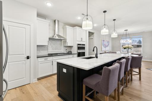 Dream kitchen boasts sprawling center island with table seating. Note the lovely light fixtures for added ambiance over this space.