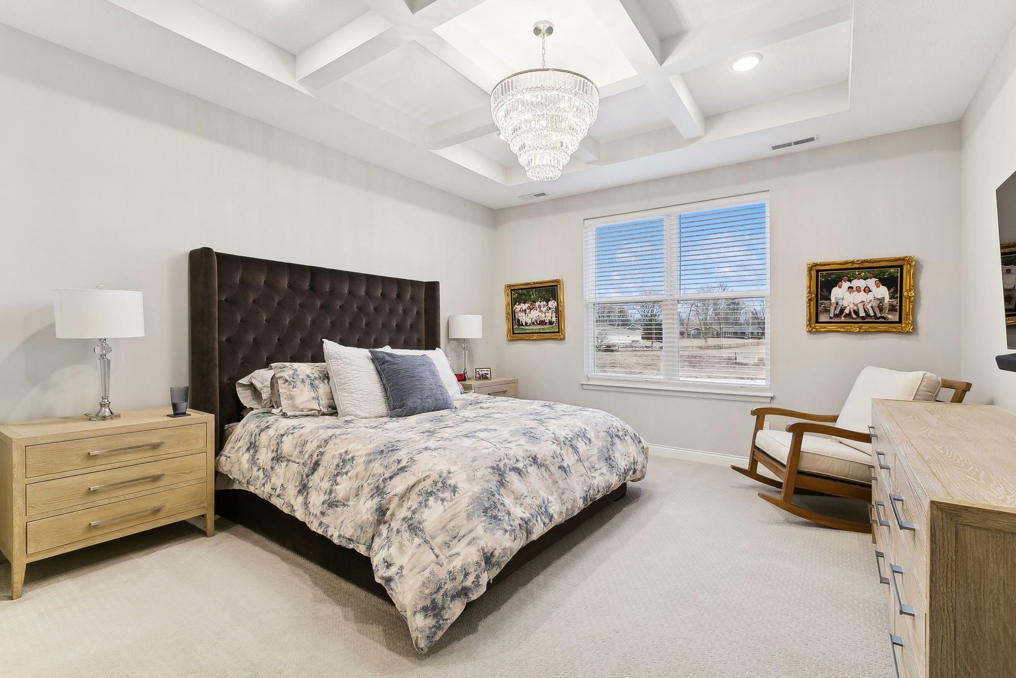 Primary bedroom with lovely natural light and a scenic view. Don't miss the upgraded coffered ceiling with recessed lighting. Note: Chandelier is NOT included in the sale.