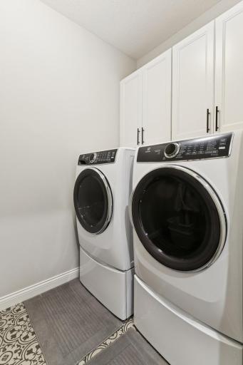 Laundry room with cabinet space and hanging for storage and organization. Washer and dryer are on pedestals for easier loading.