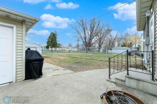 Back steps to concrete patio & fenced yard with storage shed
