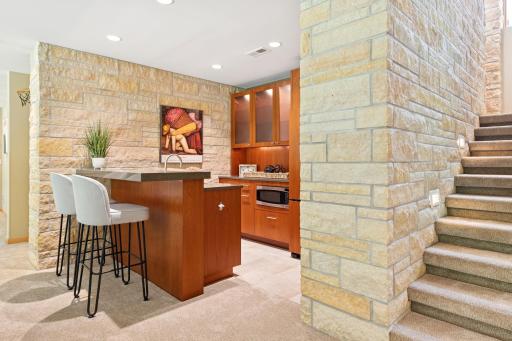 Adorned by hand chiseled stone this kitchenette is prepared to serve with refrigerated beverages, hot snacks & a dishwasher for easy clean up.