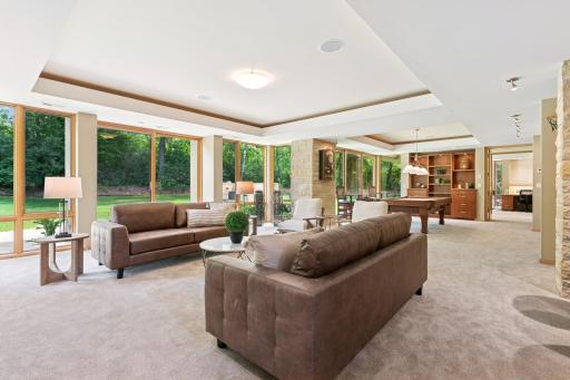 A family & friends room, flowing into the billiards space & beyond the French doors, a studio & more. Specialty lighting in each ceiling feature. The views are all plush greenery. Also, new carpeting is here.