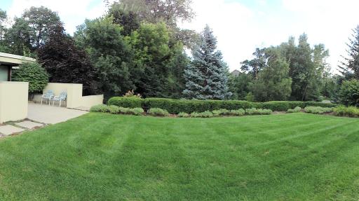 Until your tour, please allow this panorama photo of the front yard to show you the plush landscapes that await you. From the front outdoor kitchen & patio to ornamental trees, flowers & shrubs. Please see other photos for more garden images.