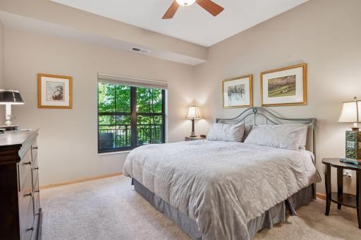 The primary bedroom is large and accommodates the king sized bed and end tables. It looks out over the balcony and tree canopies - good privacy! More high quality window treatments are at the windows and note the ceiling fan.