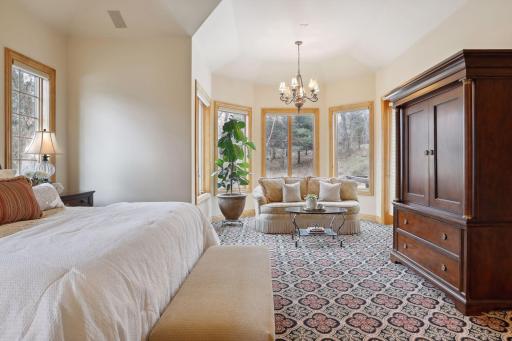 The primary bedroom features a sitting space surrounded by windows and deck access.