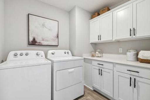 Convenient upper-level laundry room with cabinets for plenty of storage. Photo of a model home, color & options will vary.