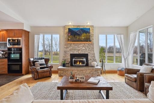 This accent wall is adorned with expansive windows, perfectly complementing the striking stone fireplace surround as a captivating focal point