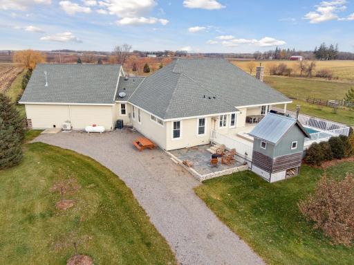 The back of the home features an expansive deck with a built-in pool, sauna house, stone patio, and propane access or extra parking!