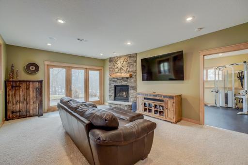 The walkout lower level is an entertainerâs dream, showcasing a roomy living area with a cozy fireplace, a theater room with projector and screen, and a stunning rustic bar outfitted with granite counters, a sink, fridge, and wine fridge.