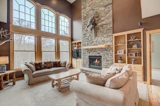 The living room, open to the upper level balcony, features a striking fireplace.