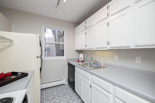 White cabinets, dishwasher, electric stove and updated flooring
