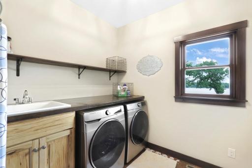 The main floor laundry room features a large sink, folding counter, extra shelving and side-by-side Samsung frontload washer and dryer.